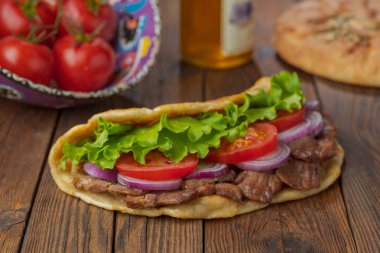 Kavrulmuş et, domates, soğan ve marul mutfak masasında lezzetli taze ev yapımı pita sandviç. 