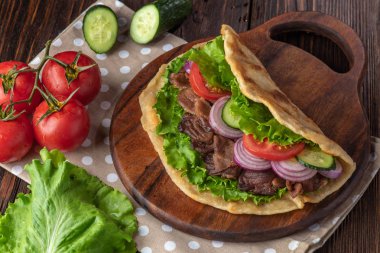 Sığır eti ve sebze lekeli havlu ile ahşap tahta üzerinde taze tortilla sandviçle