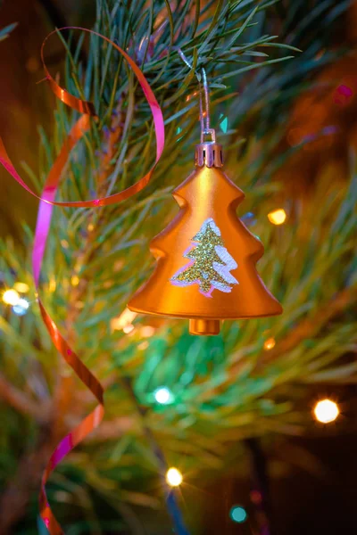 Gold tree shaped Christmas ornament on festive fir tree background