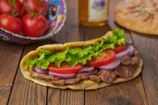 Kavrulmuş et, domates, soğan ve marul mutfak masasında lezzetli taze ev yapımı pita sandviç. 