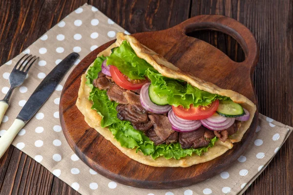 Sığır eti ve sebze lekeli havlu ile ahşap tahta üzerinde taze tortilla sandviçle