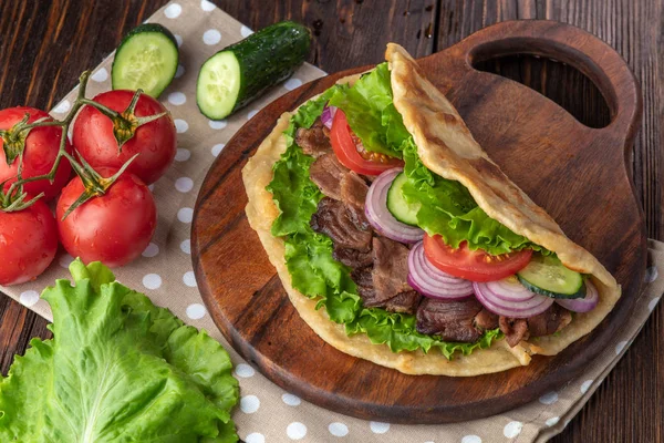 Sığır eti ve sebze lekeli havlu ile ahşap tahta üzerinde taze tortilla sandviçle