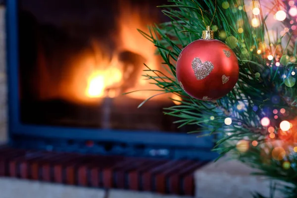 Kalp desenli Noel süs köknar ağacı üzerinde yanan şömine arka plan üzerinde kırmızı top