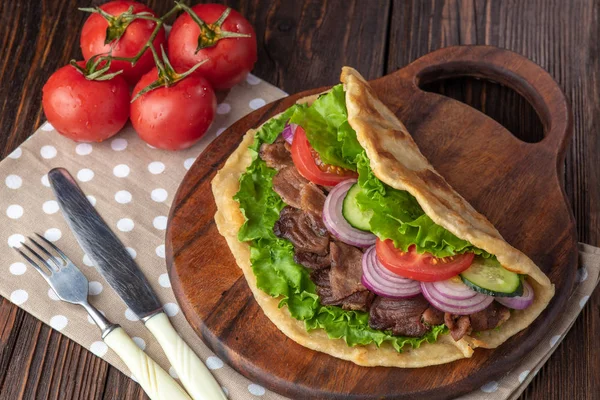 Sığır eti ve sebze lekeli havlu ile ahşap tahta üzerinde taze tortilla sandviçle