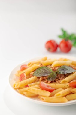 Beyaz arka planda domates ve fesleğen yaprakları ile taze bolonya makarna Tabak