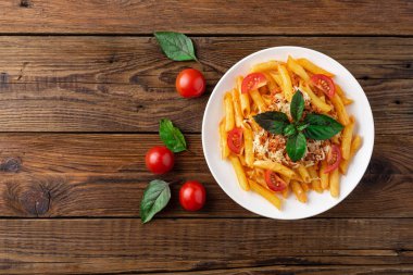 Ahşap masa üzerinde domates ve fesleğen yaprakları ile taze bolonya makarna Tabak
