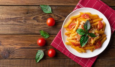 Ahşap masa üzerinde havlu üzerinde domates ve fesleğen yaprakları ile taze bolonya makarna Tabak