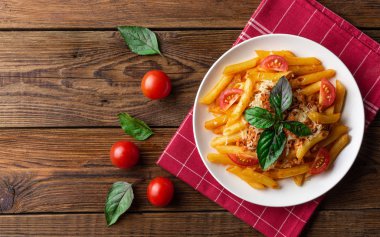 Ahşap masa üzerinde havlu üzerinde domates ve fesleğen yaprakları ile taze bolonya makarna Tabak