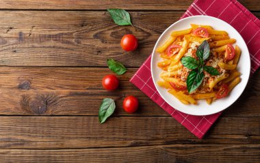 Ahşap masa üzerinde havlu üzerinde domates ve fesleğen yaprakları ile taze bolonya makarna Tabak