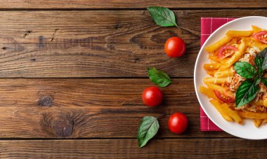 Ahşap masa üzerinde havlu üzerinde domates ve fesleğen yaprakları ile taze bolonya makarna Tabak