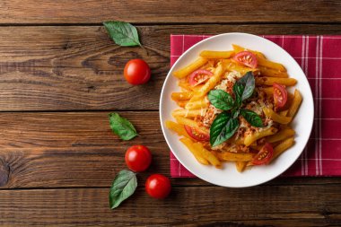 Ahşap masa üzerinde havlu üzerinde domates ve fesleğen yaprakları ile taze bolonya makarna Tabak