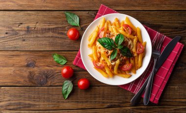 Ahşap masa üzerinde havlu üzerinde domates ve fesleğen yaprakları ile taze bolonya makarna Tabak