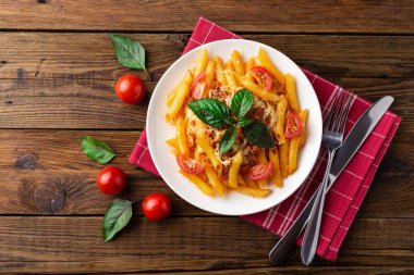 Ahşap masa üzerinde havlu üzerinde domates ve fesleğen yaprakları ile taze bolonya makarna Tabak