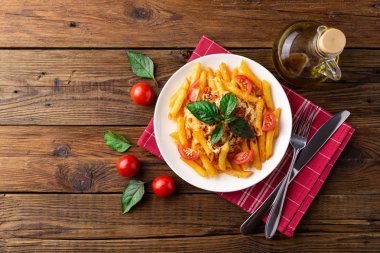 Ahşap masa üzerinde havlu üzerinde domates ve fesleğen yaprakları ile taze bolonya makarna Tabak