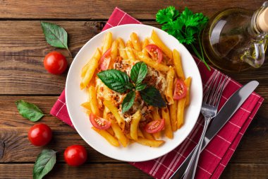 Ahşap masa üzerinde havlu üzerinde domates ve fesleğen yaprakları ile taze bolonya makarna Tabak