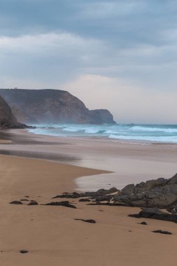 Praia da Mareta fırtınalı havalarda doğal kumlu plajda Rocks, Portekiz