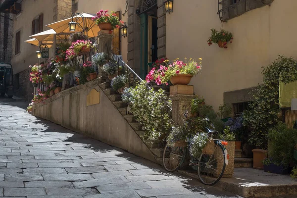 Street scene with parked bicycle by ancient building in Cortona, Arezzo, Tuscany, Italy.