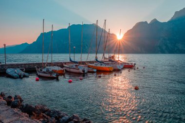 Yachts moored at pier during sunset on Lake Garda in mountains, Riva del Garda, Italy, Europe