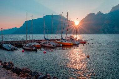 Yachts moored at pier during sunset on Lake Garda in mountains, Riva del Garda, Italy, Europe