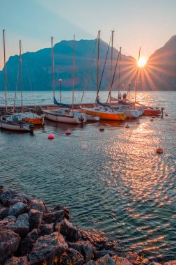 Yachts moored at pier during sunset on Lake Garda in mountains, Riva del Garda, Italy, Europe