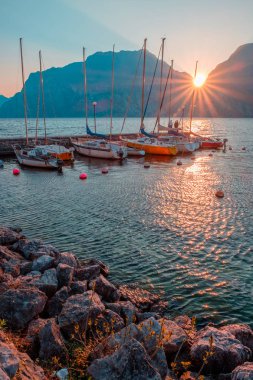 Yachts moored at pier during sunset on Lake Garda in mountains, Riva del Garda, Italy, Europe