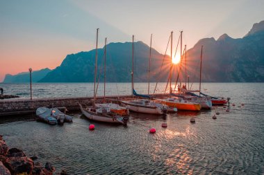 Yachts moored at pier during sunset on Lake Garda in mountains, Riva del Garda, Italy, Europe