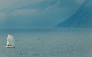 Şafakvakti dağ manzarasında deniz suyunda yelkenli tekne ile Sahne, Toskana, İtalya