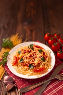 Domates soslu makarna ve kıyma, rendelenmiş parmesan peyniri ve taze maydanoz - sade ahşap arka planda ev yapımı İtalyan makarnası.. 