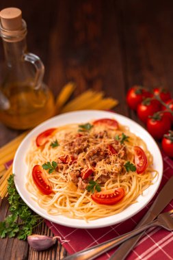 Domates soslu makarna ve kıyma, rendelenmiş parmesan peyniri ve taze maydanoz - sade ahşap arka planda ev yapımı İtalyan makarnası..