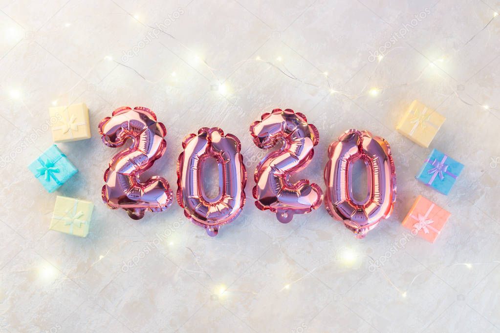 Pink numbers 2020 on a white background. A garland of stars shimmering with colorful lights.