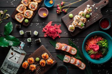 Suşi, rulo ekmek ve koyu arkaplanda geleneksel Japon yemekleri ile servis edilir. Üst görünüm.