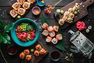 Suşi, rulo ekmek ve koyu arkaplanda geleneksel Japon yemekleri ile servis edilir. Üst görünüm.