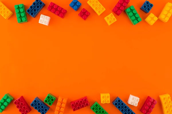 Haufen Spielzeugfarbener Plastikblöcke Und Farbiger Spielzeugsteine Auf Orangefarbenem Hintergrund Kopierraum — Stockfoto