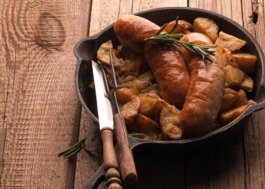 patates kızartması ve sosis, çatal ve bıçak ahşap arka plan üzerinde tava