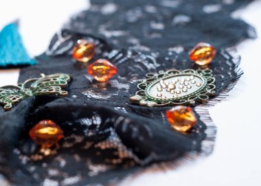 Beyaz arka planda siyah dantel dekoratif yeşil kelebek, turuncu boncuk, çerçeve ve Rhinestones seçici odak