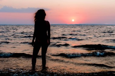 Mayo ayakta ve sahilde denize yakın inanılmaz gündoğumu bakarak ince kadın rakam geri görünümü