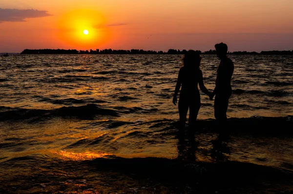 Cherkasy, Ukrayna-08.14.2018: şafakta suda sahilde kadın ve adam siluetleri