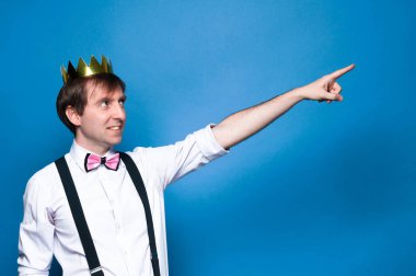 gömlek, askı, Bow kravat ve altın taç, gülümseyen, uzağa bakarak ve kopya alanı ile mavi arka planda mesafe içine parmak ile Ponting yakışıklı adam