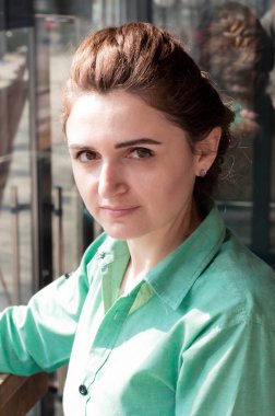 kahve dükkanında pencere yakınında kameraya bakarak yeşil gömlekli kadın portresi