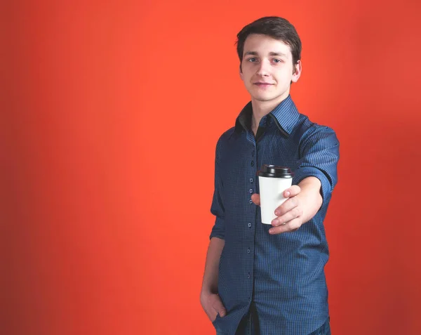 Красивый Молодой Человек Бумажной Чашкой Кофе Протянутой Руке Глядя Камеру — стоковое фото