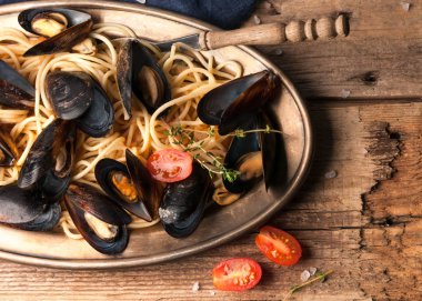 domates soslu lezzetli makarna üst görünümü ve ahşap dokusal arka plan üzerinde çatal ile metal plaka üzerinde pişmiş midye