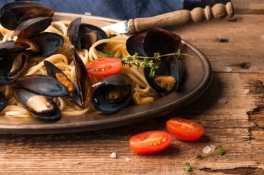 lezzetli geleneksel İtalyan spagetti ve midye ahşap arka plan üzerinde domates ile metal plaka üzerinde sos pişmiş