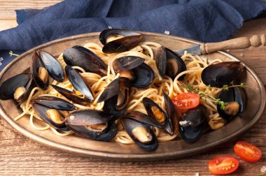 deniz ürünleri ve metal plaka ve ahşap dokusal arka plan üzerinde dilimlenmiş kiraz domates ile lezzetli makarna