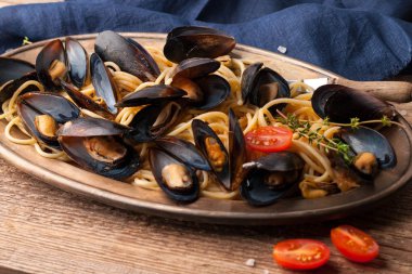 ahşap dokusal arka plan üzerinde dilimlenmiş domates ve biberiye ile kabukları makarna ve midye ile altın plaka