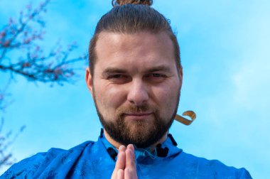 mavi kimono samuray düşük açı görünümü, mavi gökyüzü önünde kameraya bakarak clasped elleri ile ayakta