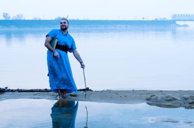 mavi kimono gülümseyen sakallı adam ahşap sopa ve kitap ile sis nehir kıyısında ayakta ve kamera bakarak