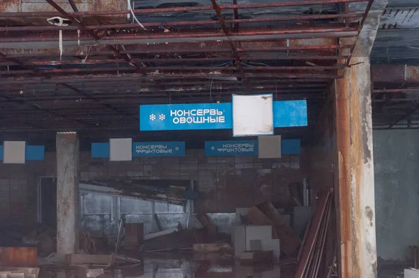 blue signs with inscriptions and broken furniture in destroyed shop in Pripyt, Chernobyl zone of alien