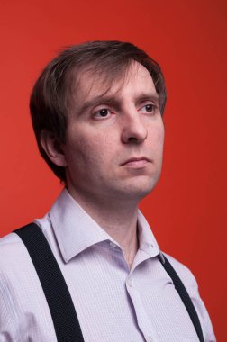 pembe gömlek ve siyah askı lı koyu saçlı yakışıklı kendine güvenen adam portresi uzak mercan arka plan üzerinde bakıyor