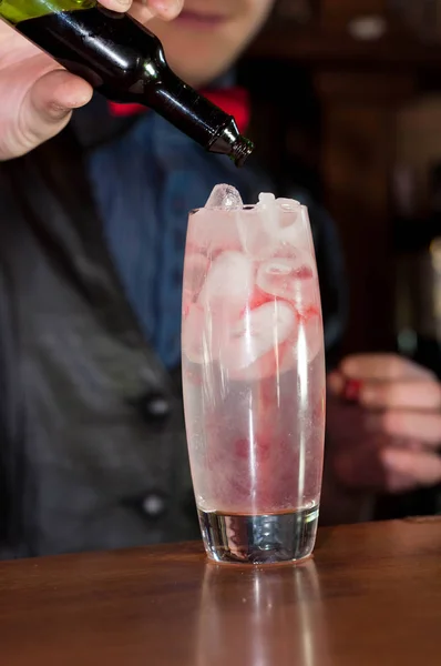 レストランのバーカウンターでアルコールカクテルとアイスキューブとガラスに赤いグレナディンシロップを注ぐバーマンの手の選択的な焦点 — ストック写真