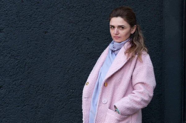 pembe ceket ve eşarp ayakta atraktif kendine güvenen kadın yan görünümü ayakta ve kopya alanı ile siyah arka plan üzerinde cebinde el tutarak